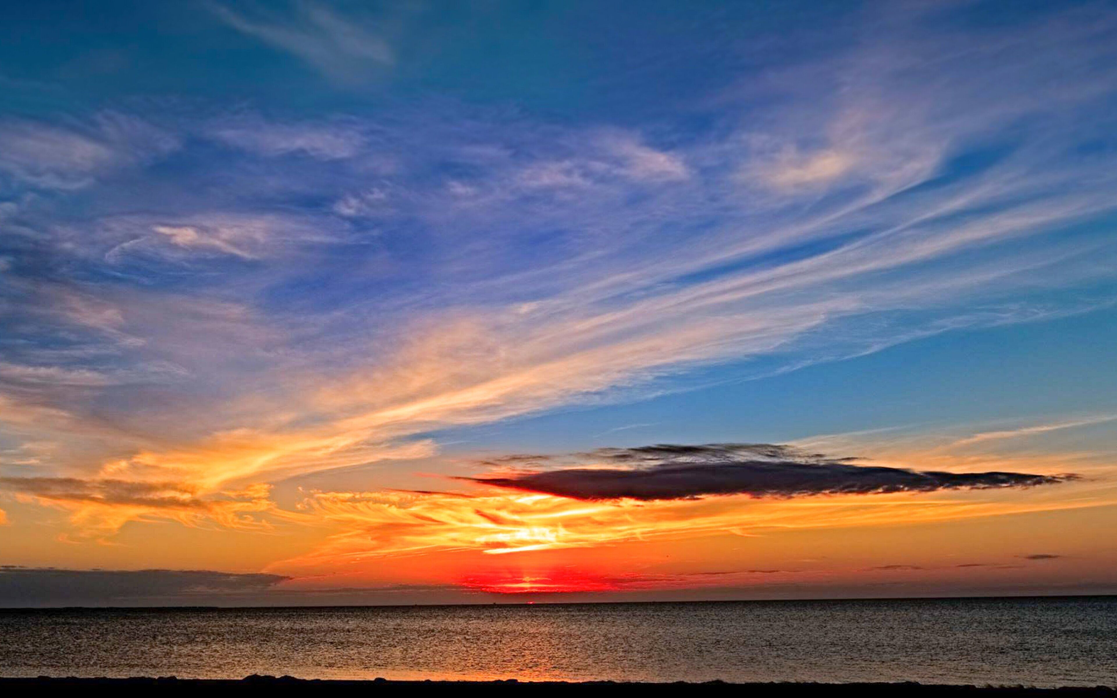 Un coucher de soleil sur une mer calme, avec un horizon dégagé.