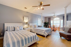 A bedroom with two beds, a ceiling fan, a desk, and a dining area. - SB72B: Coastal Suite with golf course view and shared pool access (Sunset Beach)