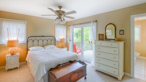 A bedroom with a bed, a dresser, a nightstand, a ceiling fan, and a view of the outdoors. - Ocean view duplex with a washer/dryer, central AC, deck, & golf nearby (North Topsail Beach)