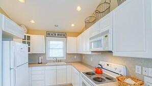A kitchen with white cabinets, a stove, and a microwave. - Water-view two-story duplex with multiple decks, outdoor shower, washer/dryer (North Topsail Beach)