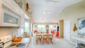 A spacious kitchen with a dining area, white cabinetry, and a large window providing natural light. - Water-view two-story duplex with multiple decks, outdoor shower, washer/dryer (North Topsail Beach)