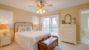 A bedroom with a bed, a dresser, a nightstand, a ceiling fan, and a window with curtains. - Water-view two-story duplex with multiple decks, outdoor shower, washer/dryer (North Topsail Beach)