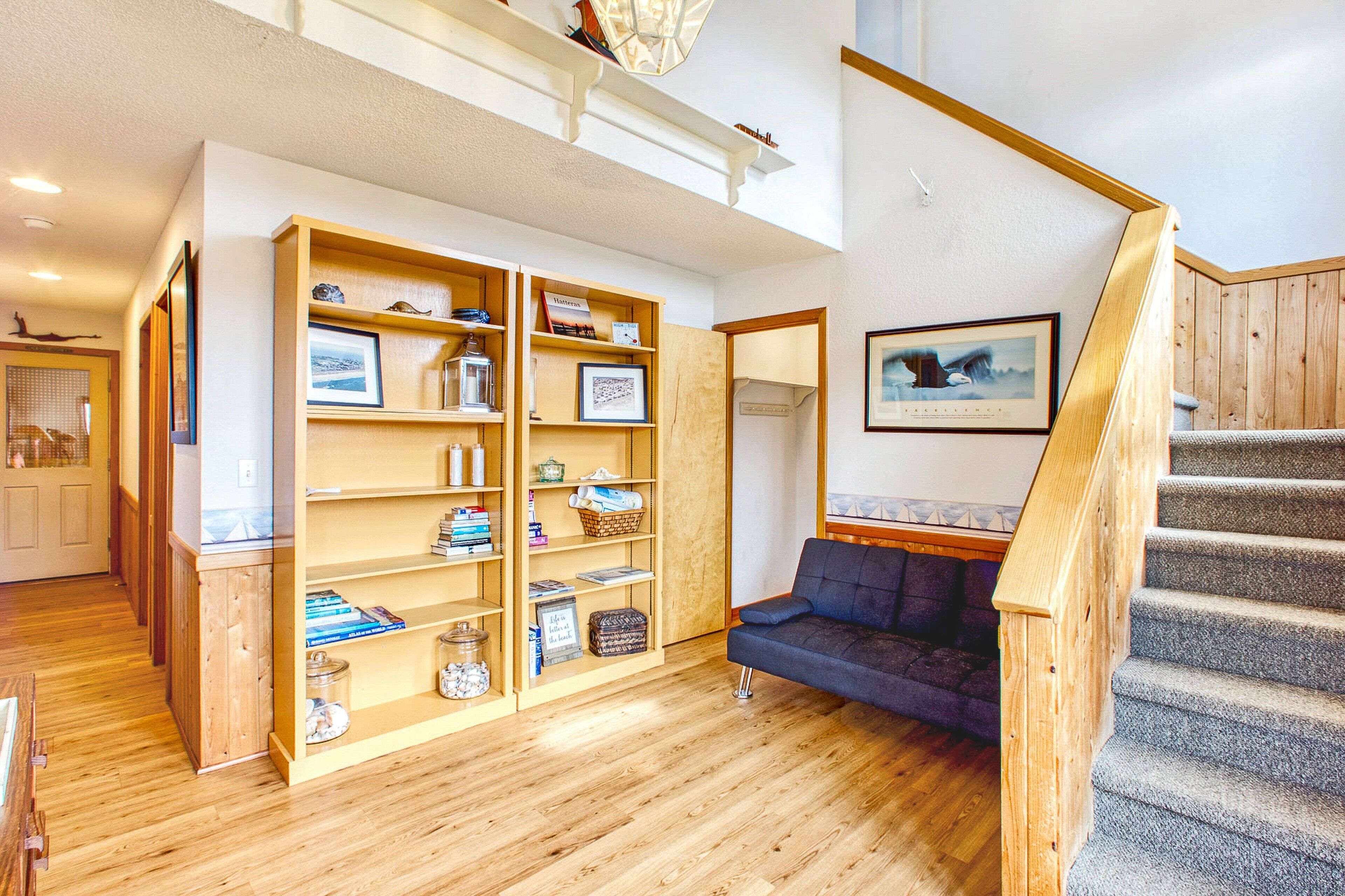 Un vaste espace de vie comprenant une bibliothèque en bois, un canapé bleu et un escalier.