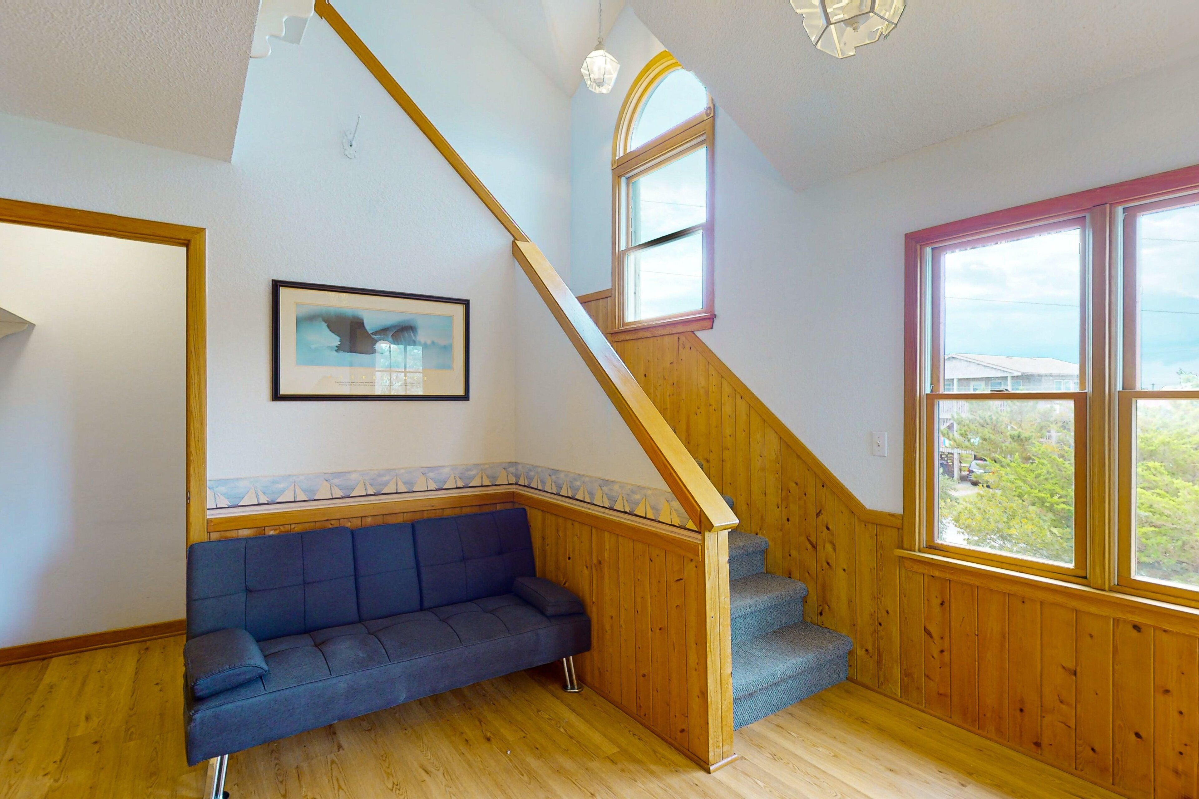 A room with a wooden staircase, a blue sofa, and a framed picture on the wall.