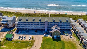 A large hotel with multiple buildings, a parking lot, and a beach view. - Oceanfront, dog-friendly condo with ocean view, central AC & WiFi (Hatteras)