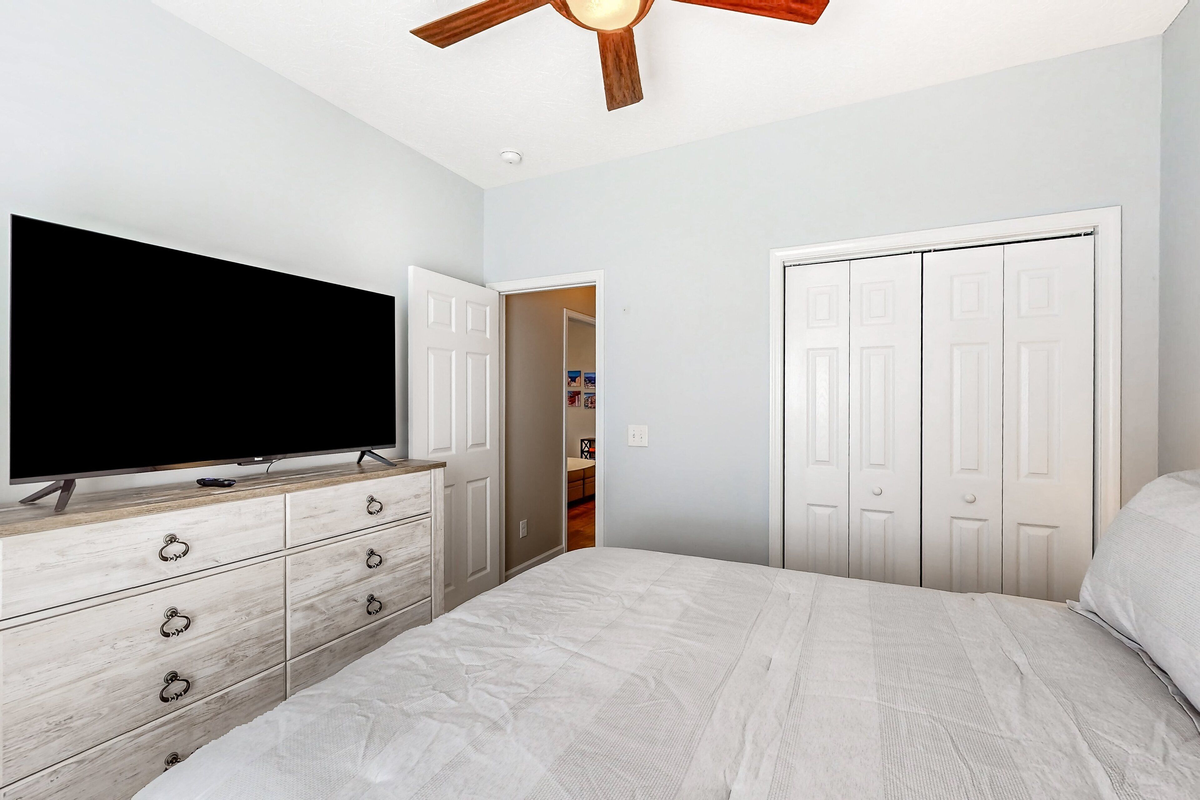 Una camera da letto con un letto, una cassettiera, una televisione e un armadio con ante.