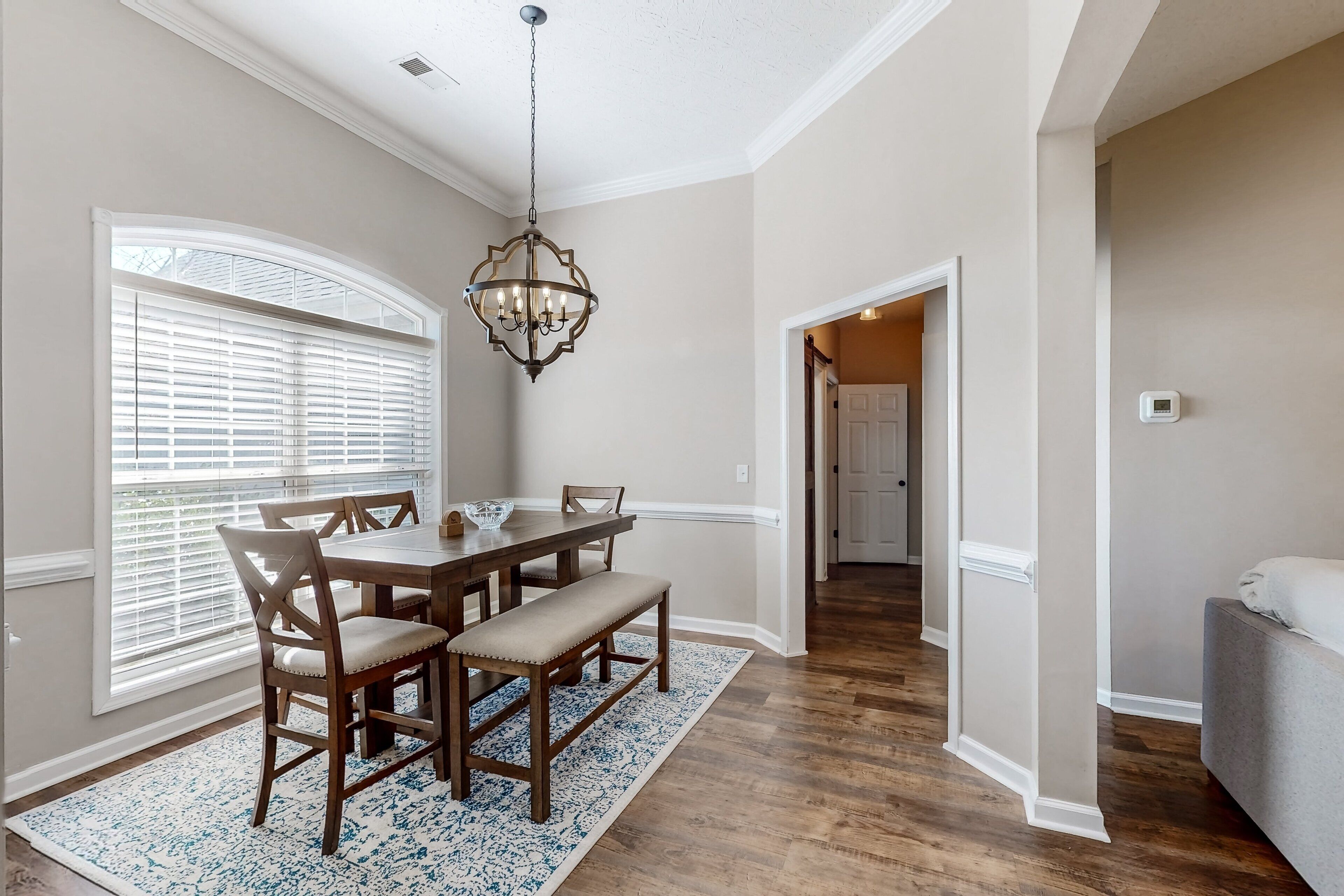 A dining room with a wooden table, chairs, and a chandelier.