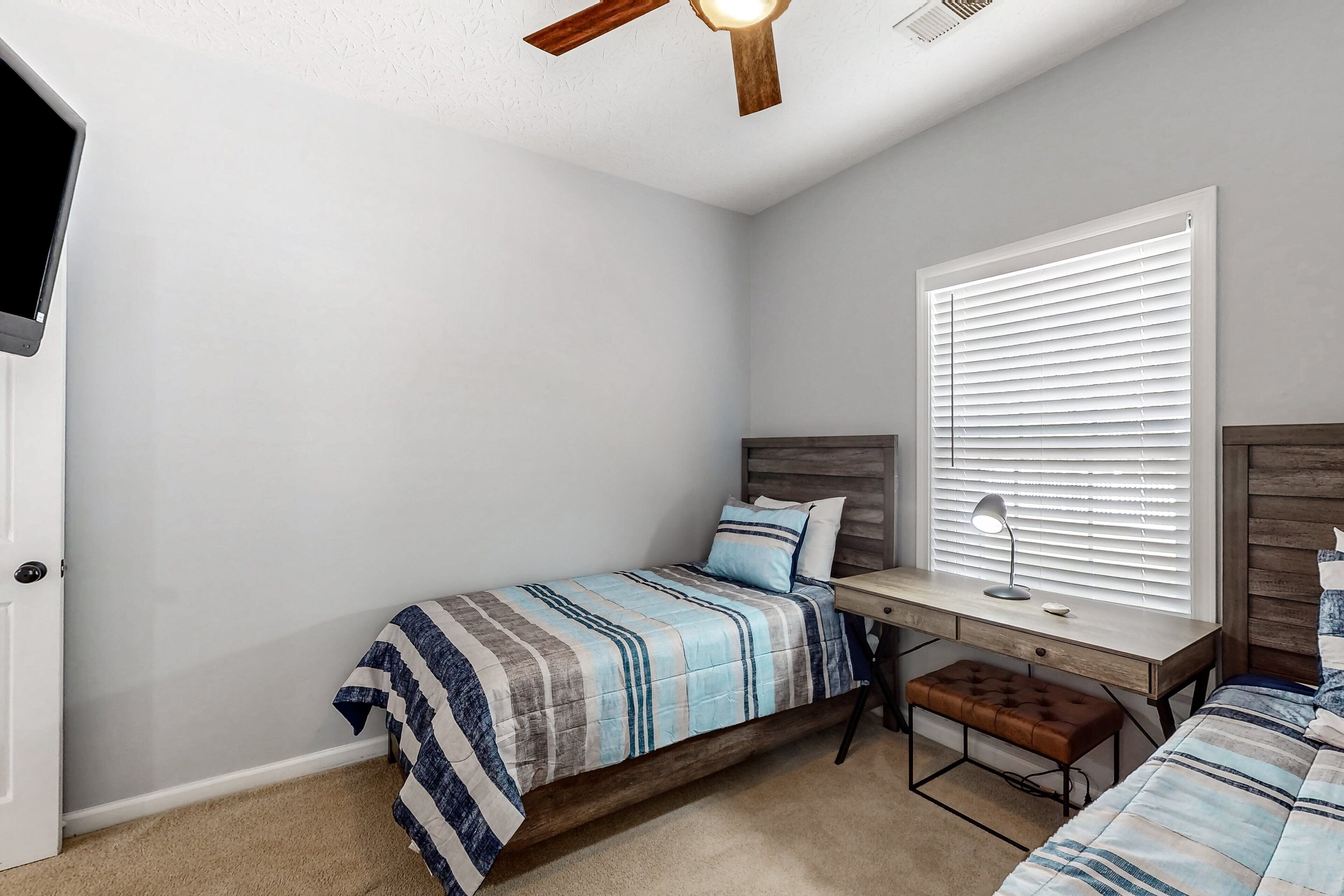 Quarto com cama, escrivaninha e janela.