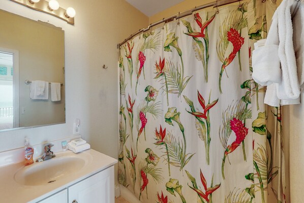 A bathroom with a white sink, a mirror, and a shower curtain with a floral pattern.