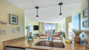 A kitchen with granite countertops, stainless steel sink, and pendant lighting. - 2nd-floor beachfront condo with ocean views, pool, sauna, tennis, balcony, & AC (North Topsail Beach)
