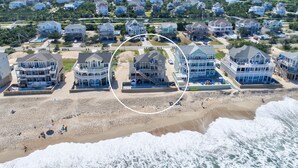Zona residencial costera con propiedades frente al mar, incluyendo casas con balcones y una piscina.