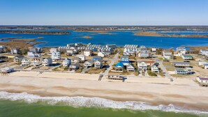 Une zone résidentielle côtière, avec des maisons le long de la plage et une vaste étendue d’eau en arrière-plan.