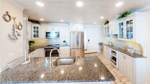 Una cocina con encimeras de granito, electrodomésticos de acero inoxidable y armarios blancos.