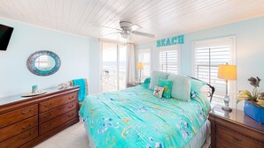 Un dormitorio con cama, cómoda, ventilador de techo y vista al océano.