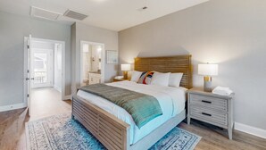 Une chambre à coucher avec un grand lit, des tables de chevet, une commode, une tête de lit en bois et un tapis à motifs.