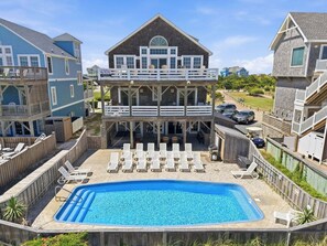 A two-story building with a balcony, a swimming pool, and lounge chairs.