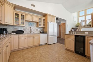 A kitchen with light wooden cabinets, a white refrigerator, and a dishwasher.