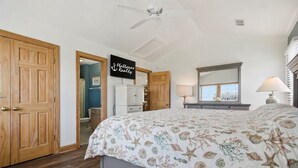 Une chambre avec un lit, un ventilateur de plafond, un miroir, une table de chevet et un panneau indiquant « Hatteras Realty ».