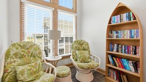 Un coin lecture avec deux fauteuils, une petite table et une bibliothèque remplie de livres.