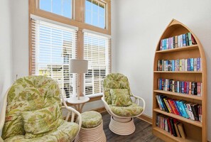 Un racó de lectura amb dues cadires, una taula petita i una estanteria plena de llibres.