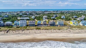 Un quartier résidentiel situé sur la côte, avec des propriétés donnant sur la plage et une plage en premier plan.