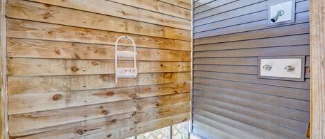 Pared externa de madeira com moldura de porta metálica e uma pequena prateleira branca.