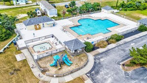 Vista aérea de una zona residencial con piscina, parque infantil y zona de patio cubierta.