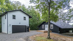 Een gebouw met twee verdiepingen, een garage, een voortuin en een klein terras.