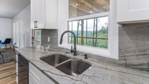 Een moderne keuken met een groot raam, een dubbele spoelbak en witte kastjes.