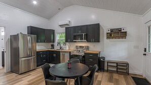 Een moderne keuken met donkere kastjes, roestvrijstalen apparatuur en een ronde eettafel met stoelen.