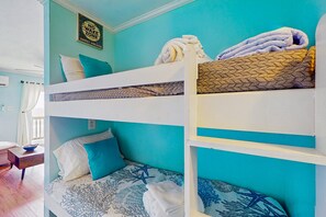 A bunk bed with a starfish-patterned bedspread, a 'No Wake Zone' sign, and a window with curtains.