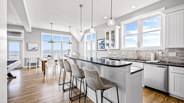 Una cocina moderna con una isla grande, taburetes de bar y vistas al océano.