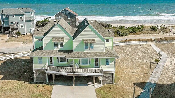 Une maison à deux étages située en bord de mer, dotée d’un balcon, d’une véranda et offrant une vue sur l’océan.