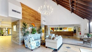 A spacious lobby with a reception desk, seating area, and a chandelier. - Oceanfront condo with pool, sauna, gym, game room, on-site restaurants, balcony (North Topsail Beach)