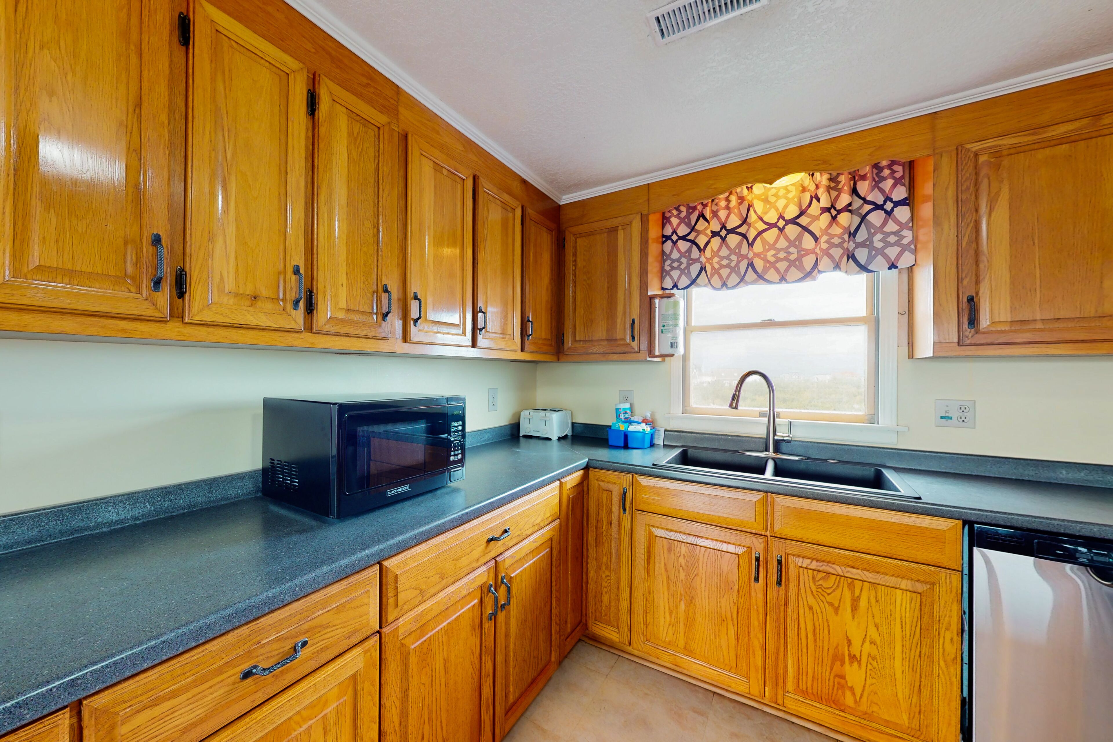 A kitchen with wooden cabinets, a microwave, a toaster, and a sink.