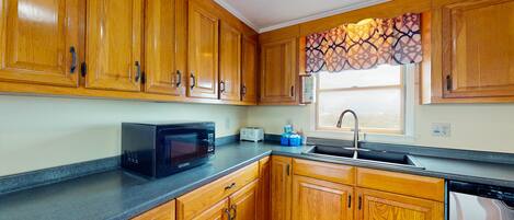 A kitchen with wooden cabinets, a microwave, a toaster, and a sink.