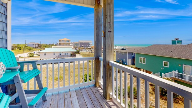 Una terraza de madera con vistas a casas de playa y al océano.