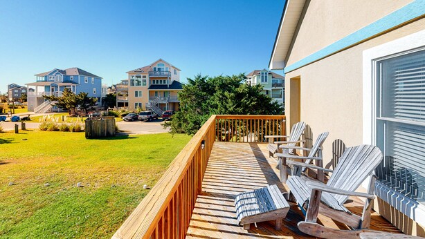 A wooden deck with lounge chairs and a view of residential buildings. - Family Condo w/Free WiFi, Central AC, Shared Pool, Private Washer/Dryer (Hatteras)