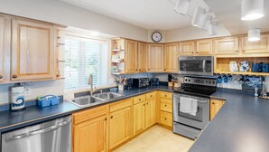 A modern kitchen with wooden cabinets, stainless steel appliances, and a large island. - Family Condo w/Free WiFi, Central AC, Shared Pool, Private Washer/Dryer (Hatteras)