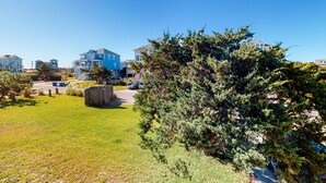 A residential area with houses, a grassy lawn, and a large evergreen tree. - Family Condo w/Free WiFi, Central AC, Shared Pool, Private Washer/Dryer (Hatteras)