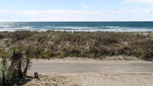 Ein Strand mit einer Straße, grasbewachsenen Dünen und einem klaren Himmel.
