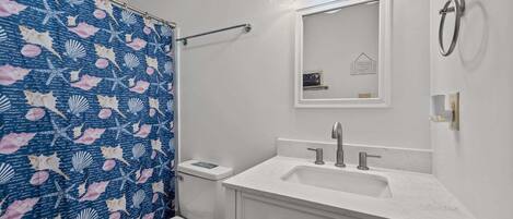 Un baño con inodoro, lavabo, espejo y cortina de ducha.