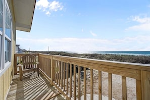 A wooden deck with a chair, overlooking a beach with sand dunes and the ocean. - Ocean-view home with stunning views and beach access across the street — 2026 New Upgrades! (North Topsail Beach)