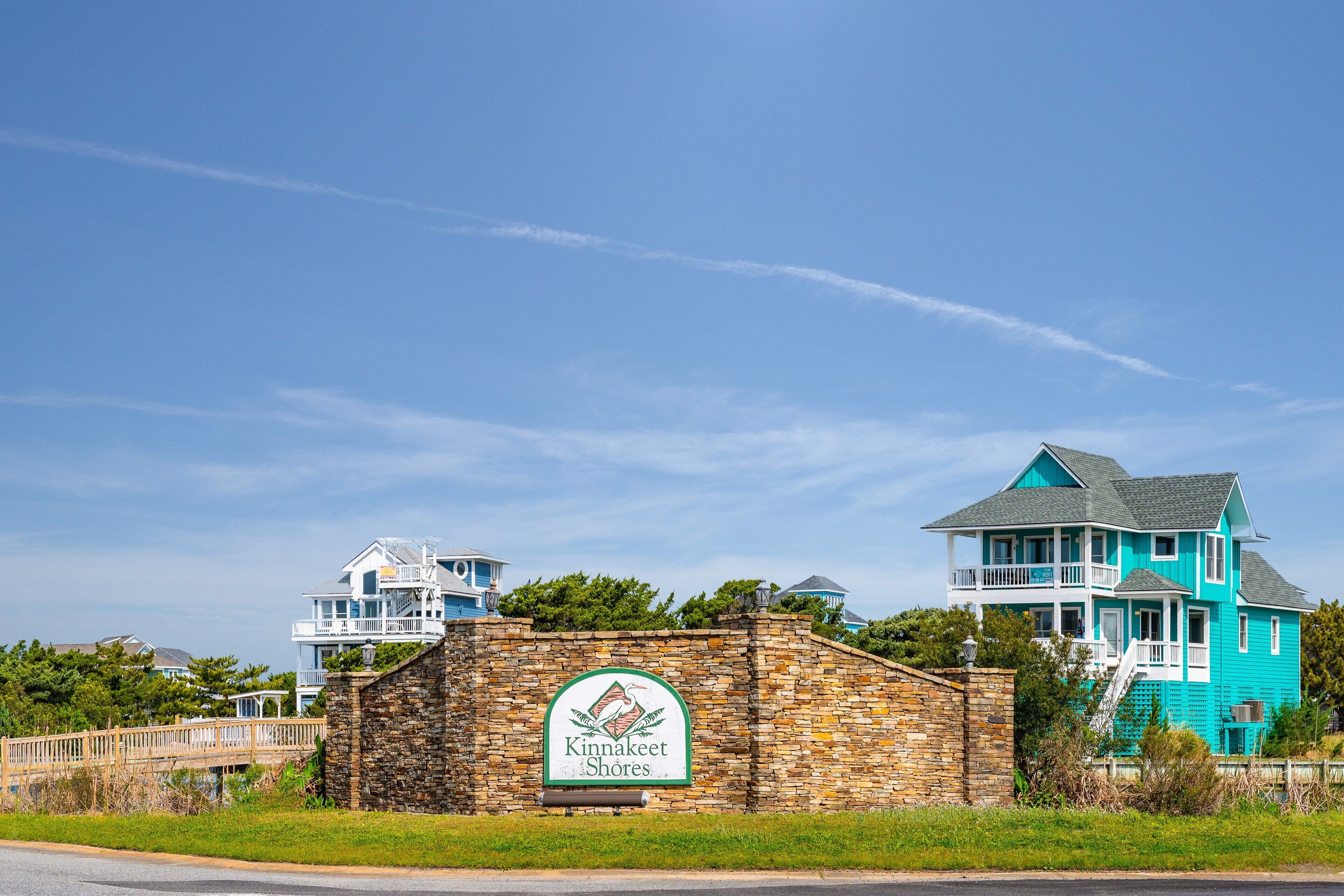 A coastal property with a stone wall and a sign for Kinnakeet Shores.
