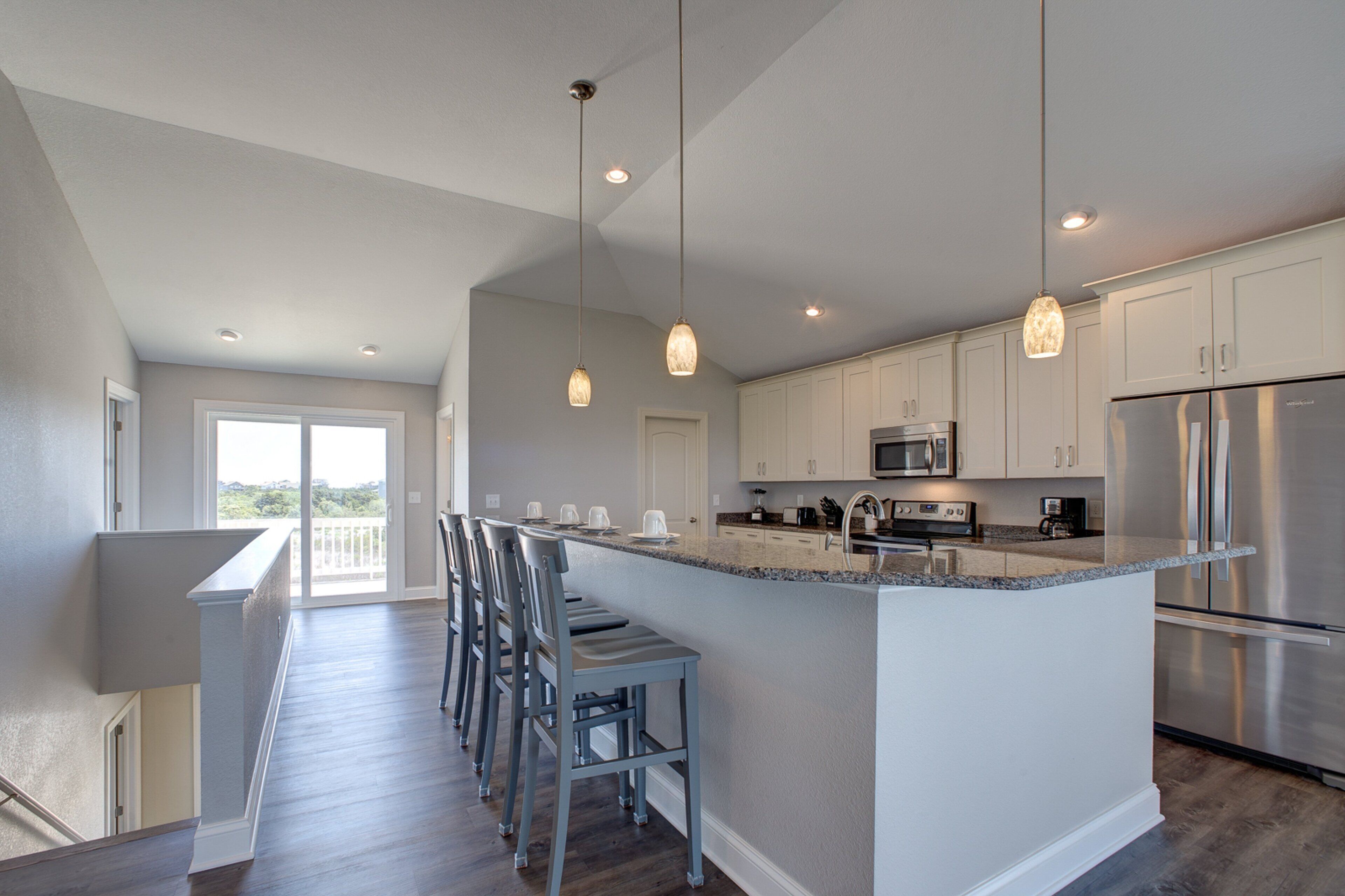 A modern kitchen with a large island, stainless steel appliances, and pendant lighting.
