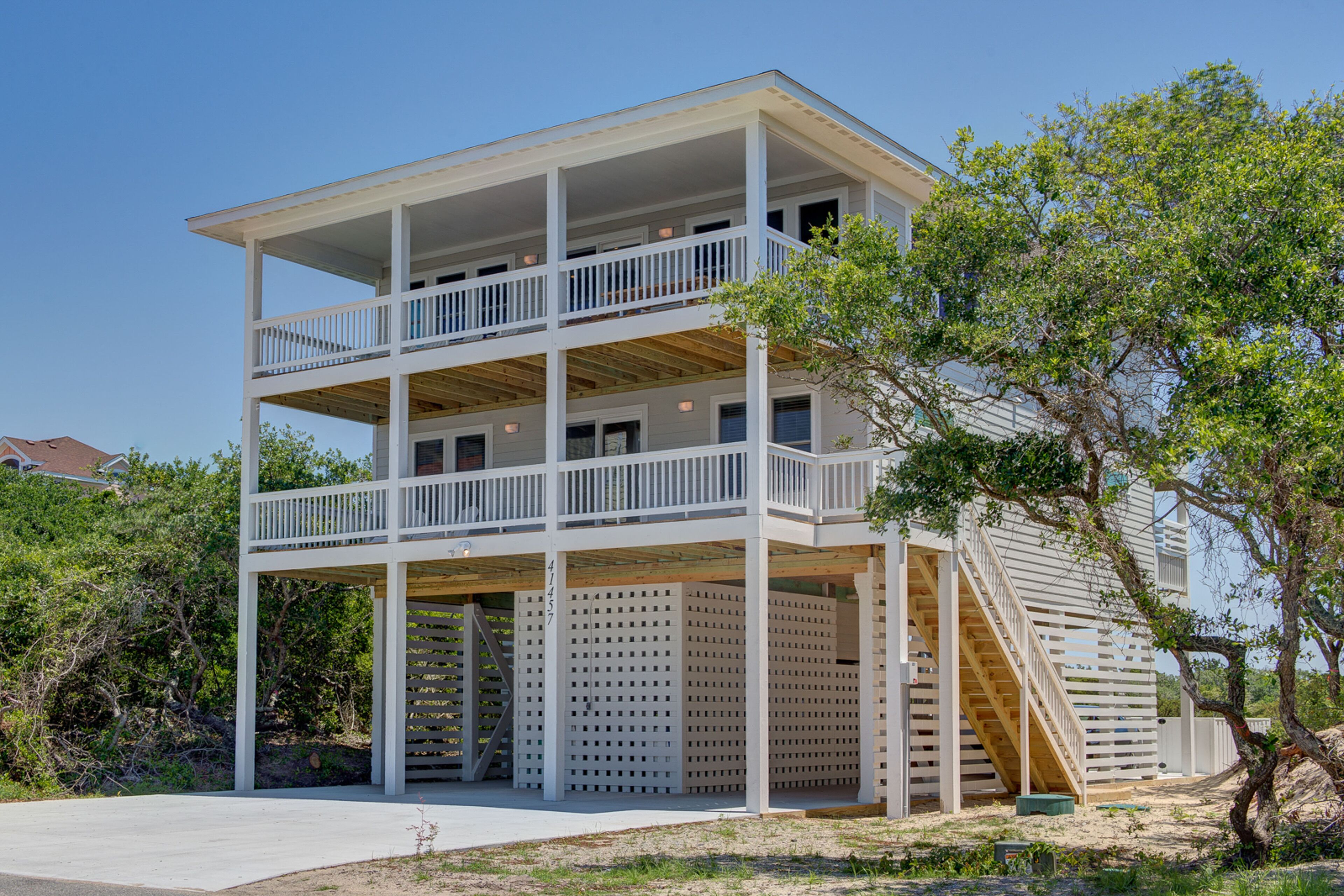 A two-story building with a balcony on the upper floor, a staircase on the right side, and a covered area with a wooden deck.
