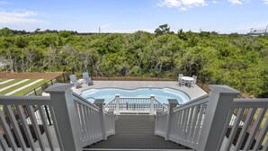 A deck with a hot tub, surrounded by a wooden fence and a view of a lush green landscape. - Oceanview Home with private pool and close beach access (North Topsail Beach)