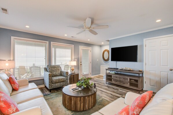 A living room with a sofa, armchair, coffee table, and a television.