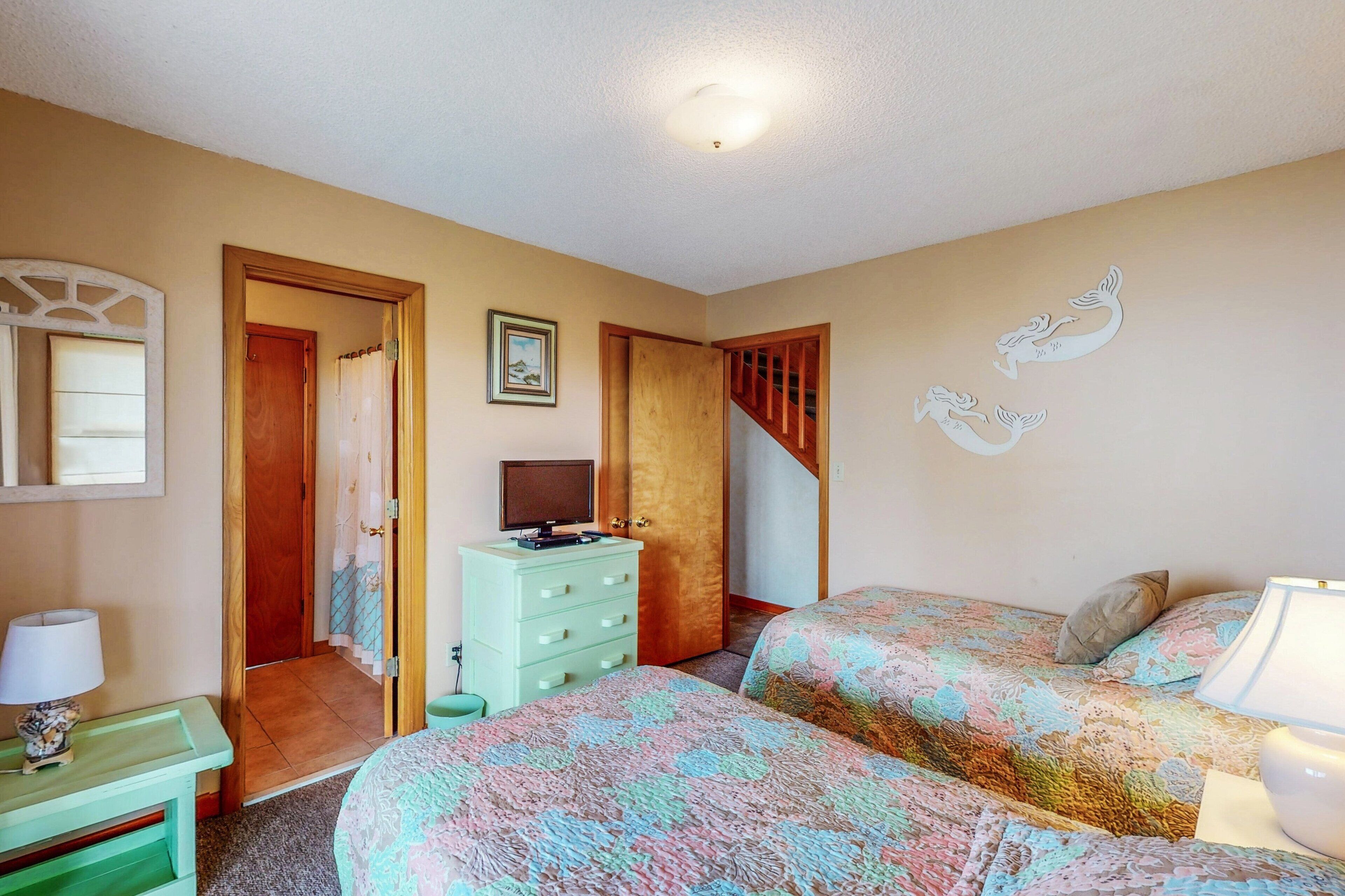 Een slaapkamer met twee bedden, een dressoir, een televisie en een trap.