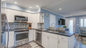 Una cocina moderna con armarios blancos, electrodomésticos de acero inoxidable y un microondas integrado.